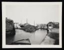 Prunella Clough, ‘Black and white photograph of a canal and towpath with factories in the background and a heap of debris on an island in the middle of the canal’ [1950s]