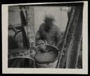 Prunella Clough, ‘Black and white photograph of a person standing by a barrel’ [1950s]