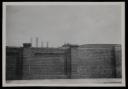 Prunella Clough, ‘Black and white photograph of a brick wall with the tops of factory chimneys visible in the background, taken at or near Bagleys Lane’ [1950s]