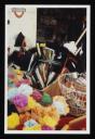 Prunella Clough, ‘Colour photograph of plastic flowers, brooms, and sponges in boxes and buckets outside a shop’ [1990s]