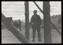 Major H. O. Daniel, ‘Photograph of guard behind the wire fence surrounding Hutchinson Internment Camp’ [c.1940–1]