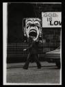 Anonymous, ‘Black and white photograph of of Dougie Thomson holding a large clown placard outside a church in Glasgow’ [c.1978]