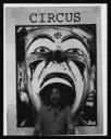 Anonymous, ‘Black and white photograph of Ian Breakwell standing, with his mouth wide open, in front of ‘Circus’, a large photo-silkscreen print of a clown’s head ’ [c.1978]
