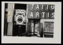 Anonymous, ‘Black and white photograph of Dougie Thomson holding a large clown placard next to a tattoo artist’s shop in Glasgow’ [c.1978]