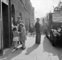 Nigel Henderson, ‘Photograph of adults and children on a busy street, fire engines at the side of the road’ [c.1949–c.1956]