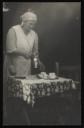 Unknown Photographer, ‘Photograph of Marie Hauptmann setting a table for tea used as the image for a blank postcard’ [c.1940s–1954] 
