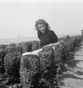 Joseph Bard, ‘Photograph of Eileen Agar sitting by concrete posts (possibly groynes) by the sea with a sailing boat in the background’ September 1938
