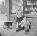 Nigel Henderson, ‘Photograph of an unidentified girl outside a shop with a toy pram and a stuffed figure’ [1949–54]