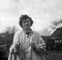 Eileen Agar, ‘Black and white glass lantern slide of Pamela Travers in a smock holding twigs with a cottage in the background’ [c.1930–60]