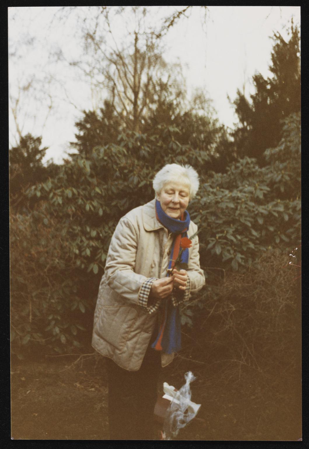 Photograph of Edith Thomas in Hanover putting a red rose