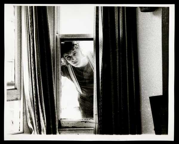 Black and white photograph of Kevin Coyne looking through a window ...