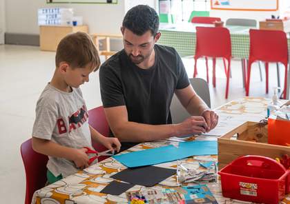 A child and parent making things using paper in Tate Liverpool's studio