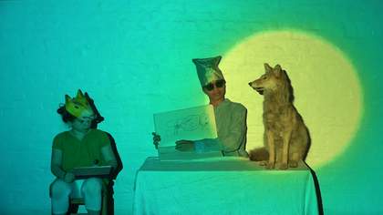 two children sit near a table, drawing a stuffed fox