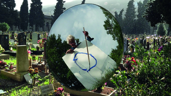 man standing in graveyard painting a circle 