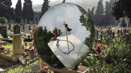Reflection of Joan Jonas drawing from a mirror placed in a graveyard
