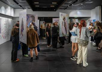 A photograph of The Threads that Bind Us exhibition with people looking at the artworks