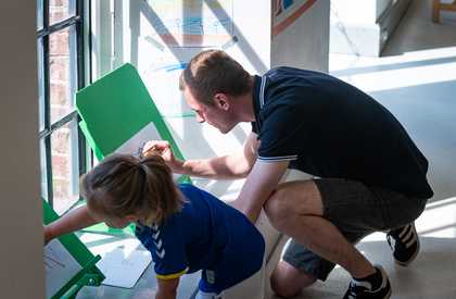 A dad and child drawing at an easel by a window