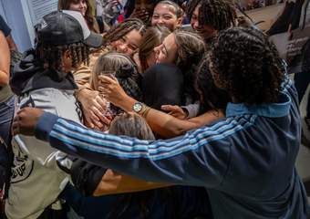 A photograph of a group of young people hugging each other