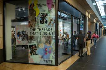 The exterior of a shop in the Metquarter with a poster in the window saying 'The Threads that Bind Us'