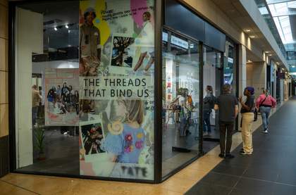 The exterior of a shop in the Metquarter with a poster in the window saying 'The Threads that Bind Us'