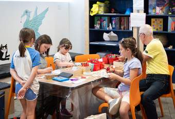 Children and two adults sat at a craft table making things.