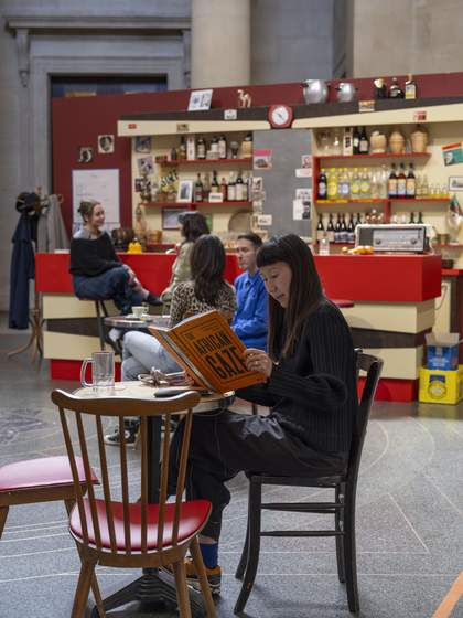 People reading and interacting with the installation of a recreation of a 1970s Algerian cafe in Paris
