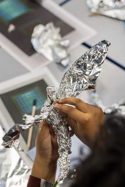 A student moulds tinfoil into the shape of a bird’s body and wings.