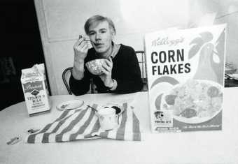 Black and white photograph of Warhol eating cereal
