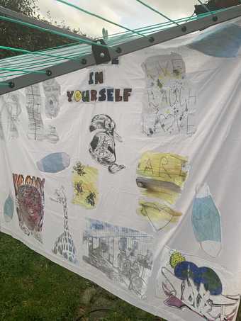 A piece of white fabric hanging from a washing line with a collage of images