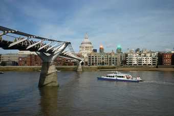 Photograph of the Millenium bridge with St Pauls in the background and two bright lights in the skyline