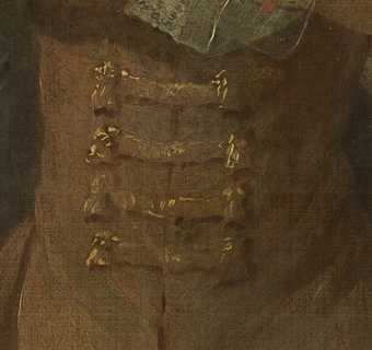 Close crop detail of long fastenings on a piece of clothing, golden brown with bright highlights