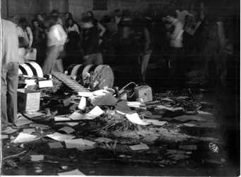 A crowd of people stand around a pile of debris