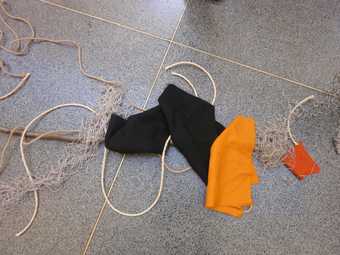 Some black and orange fabric lay on the ground alongside string