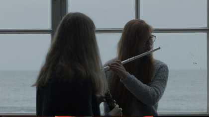 Two girls play instruments by the sea