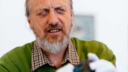 A man touches a sculpture wearing gloves