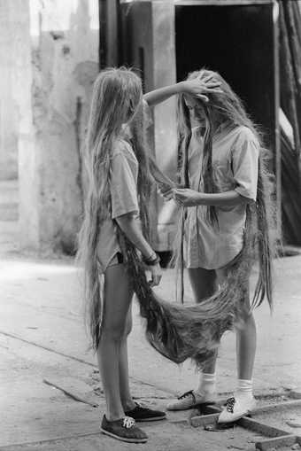 image of two young twin girls attached to each other by their long hair
