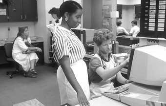 Black and white photograph of two nurses looking at a computer screen