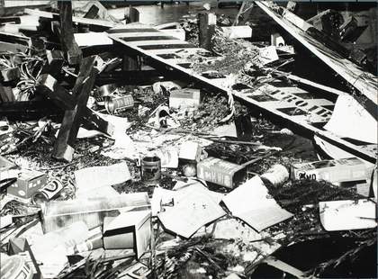 Close-up of debris including bottles, chairs, road signage, food packaging, printed material and potatoes