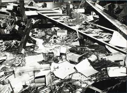 Close-up of debris including bottles, chairs, road signage, food packaging, printed material and potatoes