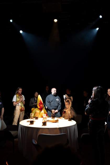 People stand and sit by a table lit by a spotlight from above.