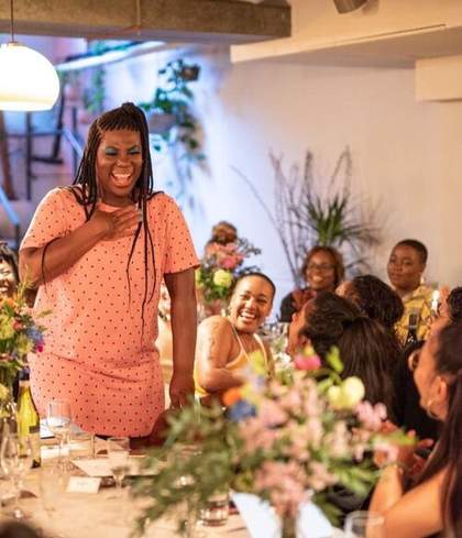 Portrait of KUCHENGA wearing a pink spotted dress laughing at an event