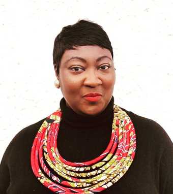 Portrait of Lady Phyll wearing a black shirt and red necklace