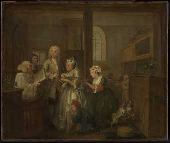 A dark interior, an elderly woman in a grand silvery white gown and a gentleman stand before someone reading from a large book