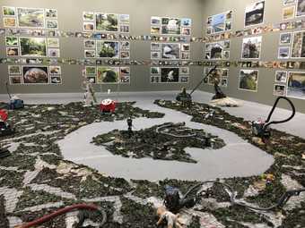installation view of a work made of plastic, with plastic objects on the floor and a cleared path through them
