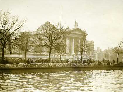 Photo of a Tate Britain and the river Thames with layers of sandbags along the river bank.