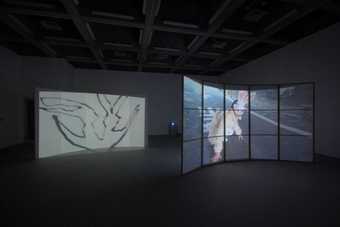 Two screens showing projected imagery in an empty gallery