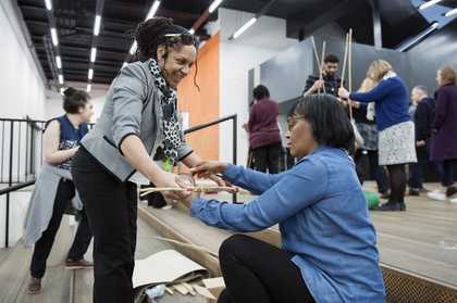 Two teachers building a tall cardboard structure