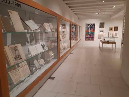 a glass case containing archive items covers the walls of a room.