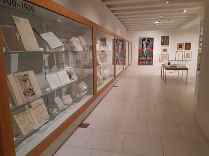 a glass case containing archive items covers the walls of a room.