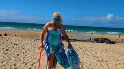 a person stands on a beach with a painted dark blue face